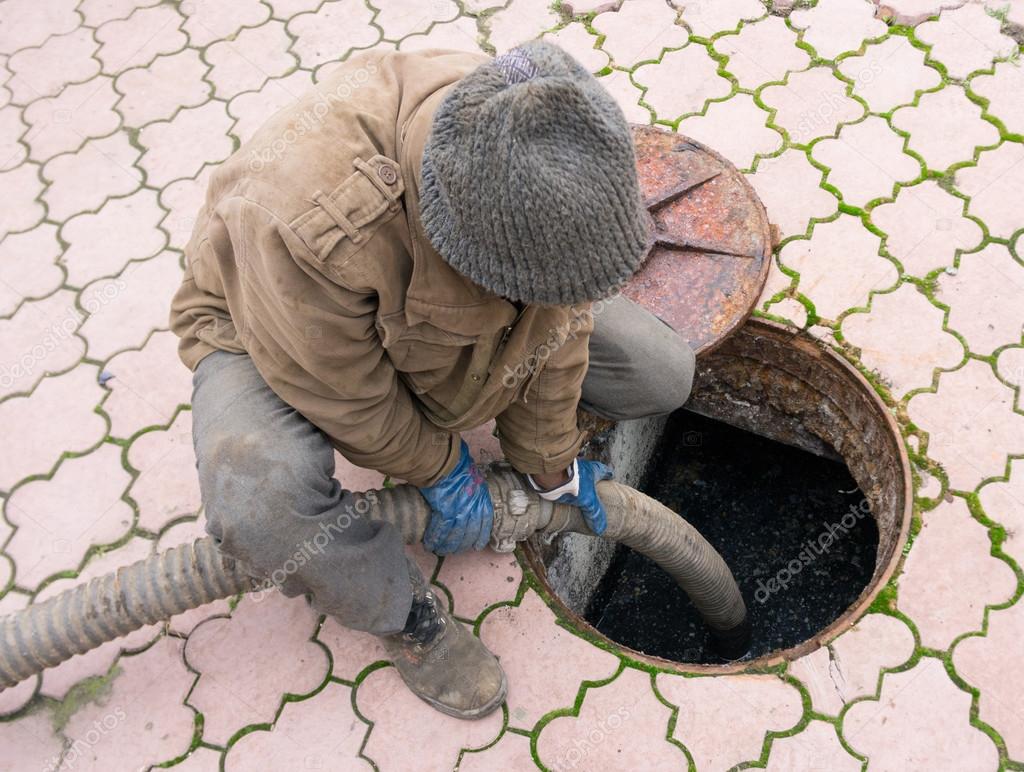 man pumping sewage from the hole