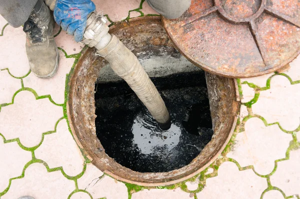 Hombre bombeando aguas residuales desde el agujero — Foto de Stock