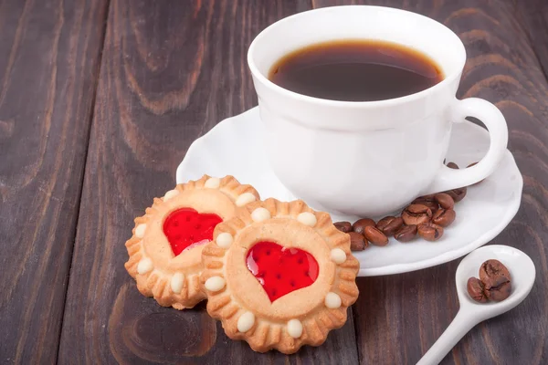 Šálek kávy s fazolemi a soubory cookie na dřevěný stůl — Stock fotografie