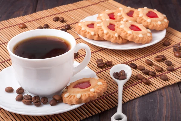 Kaffeetasse mit Bohnen und Keksen auf dem Holztisch — Stockfoto