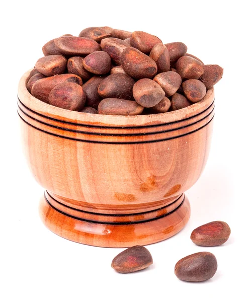 unpeeled cedar nuts in a wooden barrel on white background