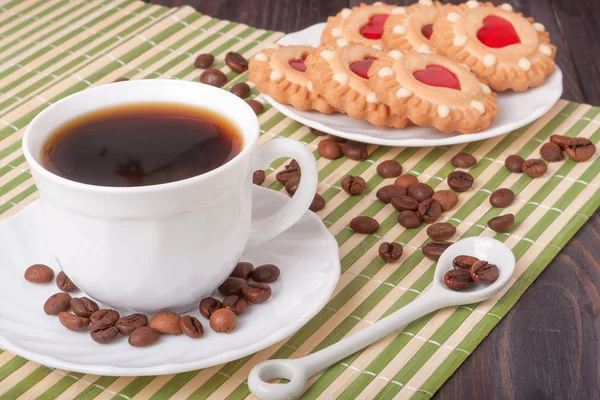 Кофейная чашка с бобами и печеньем на деревянном столе — стоковое фото