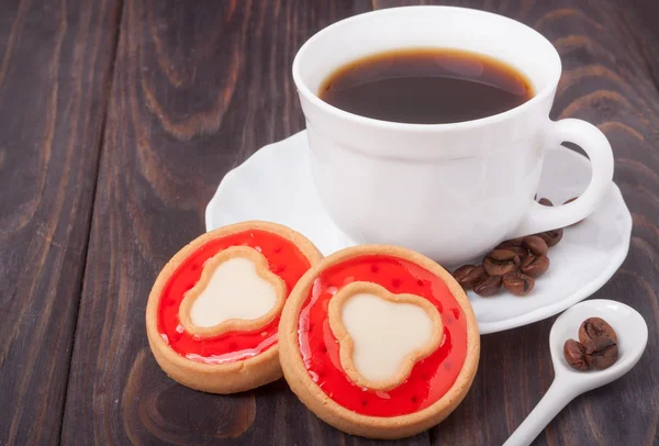 Šálek kávy s fazolemi a soubory cookie na dřevěný stůl — Stock fotografie