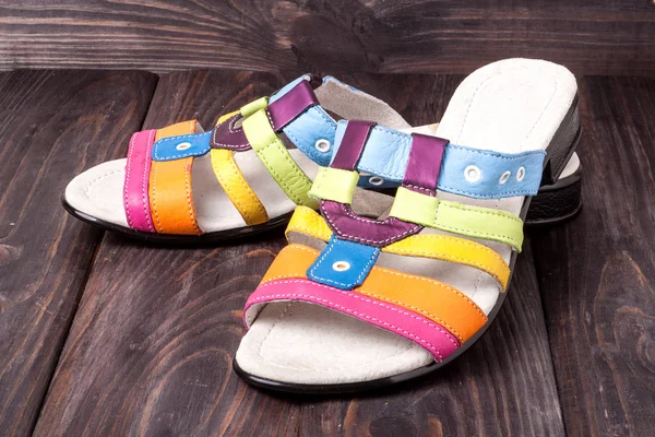colorful female low-heeled sandals on dark wooden background