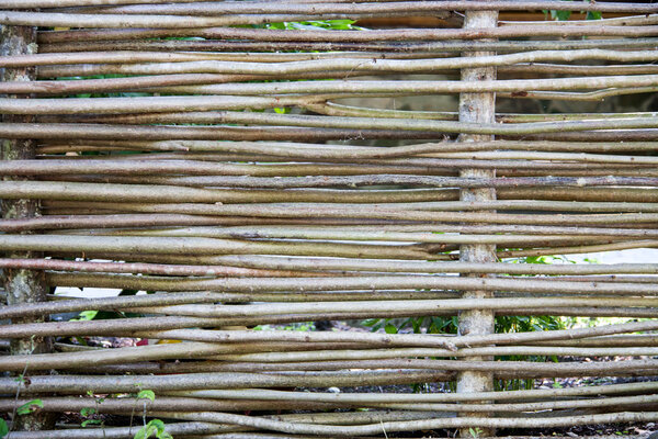 Wooden wicker fence made of sticks in the countryside.