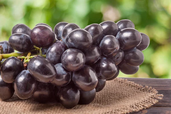 Racimo de uvas azules sobre una mesa de madera con fondo borroso — Foto de Stock