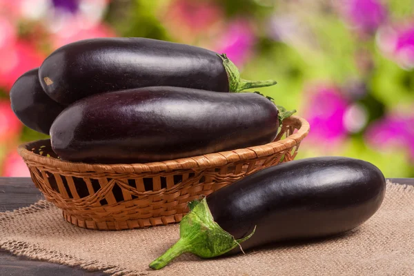 Aubergine mit einer Serviette aus Klette auf Holztisch verschwommen grünen Hintergrund — Stockfoto