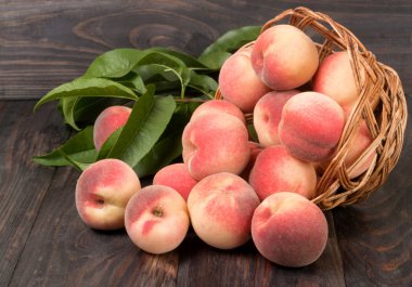 ahşap masa üzerinde bir hasır sepet şeftali