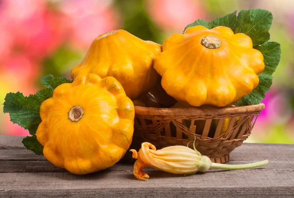 Calabaza pattypan amarillo con hoja en una canasta de mimbre sobre fondo borroso mesa de madera — Foto de Stock