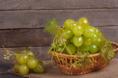 ahşap masa üzerinde bir hasır sepet içinde Yeşil üzüm