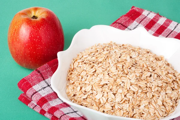 Manzanas rojas y copos de avena en un tazón —  Fotos de Stock