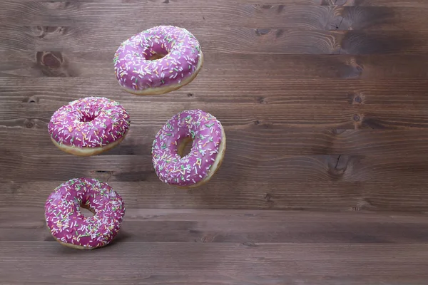 Creative food concept: levitating dounuts on wooden background