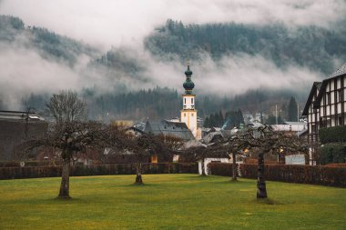 Avusturya köyünün sonbahar mevsiminde açık hava manzarası Ekim manzarası kilise kulesi ve sabah sisli havada çıplak dallar.