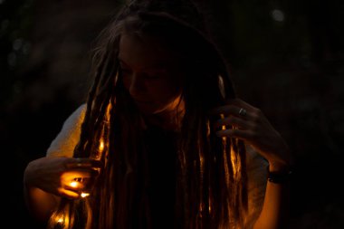 yumuşak odak portresi korkunç saçı ve turuncu ılık lambasıyla gece vakti aydınlatma ve her yerde siyah çevre alanı olan bir kız.