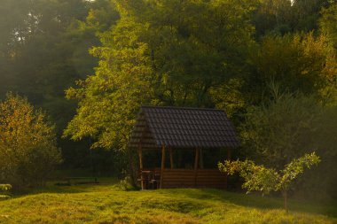 Bahar Nisan sabahı kırsal manzara manzaralı park açık hava alanı, güneşli ışık parlayan ahşap bir çardak.