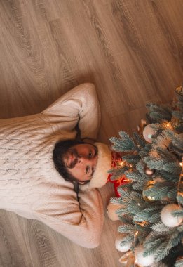 Noel ağacının altında sakin bir yetişkin adam. Aralık ayındaki kış tatilinden sonra dinleniyor. Dikey duvar kâğıdı poster resmi.