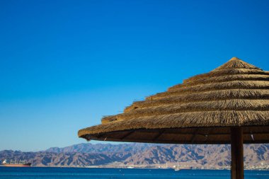 Yazın açık hava gününde açık hava manzaralı saman şemsiyesi, haziran ayının mavi arka plan görüntüsü.