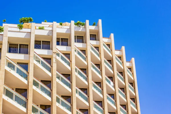 rustic white hotel building architecture facade exterior landmark view foreshortening from below on vivid blue sky background travel vacation destination apartments