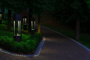 İnsanların bahçeye çıkmayacağı çevre alanı kaldırım yolu ve modern tasarım dekoratif fenerleri ile elektrik ışığıyla huzurlu bir yer.