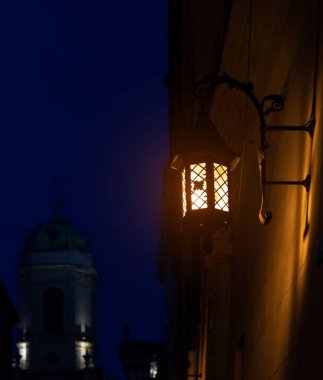 Peri masalı ortaçağ şehir manzarası. Noel zamanı lamba direği sarı güzel ışıklandırma. Hristiyan kilisesi silueti arka planda, hayalet karanlıkta.