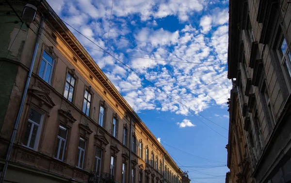 ビルの外観は雲の多い空を背景に中世の貧しい通り側の都市部の写真よりも短く — ストック写真