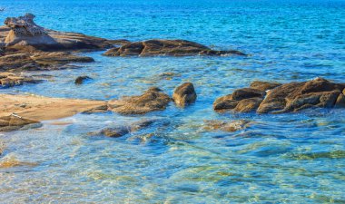 Deniz kenarındaki kayalar arka plandaki deniz sezonunun canlı renkleri.