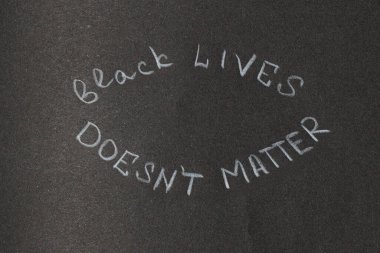 Koyu, dokulu bir geçmişe tebeşirle yazılmış bir protesto ve sosyal adalet mesajı güçlü bir beyanda bulunuyor.