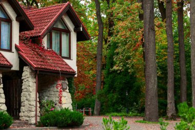 Büyüleyici taş ve sonbahar ağaçlarının arasına yerleştirilmiş kırmızı kiremit çatılı sıva ev