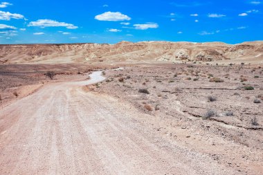 Uçsuz bucaksız bir çöl arazisinde yuvarlanan tepeler ve mavi gökyüzü