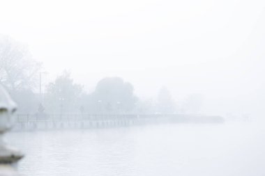 Yoğun bir sis, suyu örterek kıyı şeridini karartarak rüya gibi bir atmosfer oluşturur.