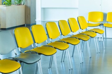 Canlı sarı ve sessiz gri sandalyeli modern oturma düzeni, toplantılar veya halk için çağdaş bir yer öneriyor.