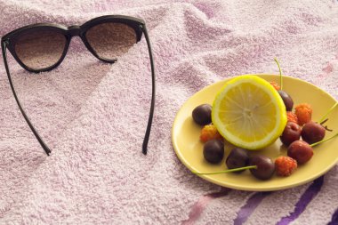 Yazın ve güneş gözlükleriyle havlunun üzerinde çeşitli meyveler olan güneşin tadını çıkarıyorum.
