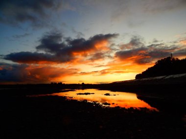 Nehrin üzerinde gün batımı. Bulutlar ve kayalar