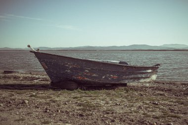 Arkadaki dağlarla birlikte göl açıklarında mavi tekne.