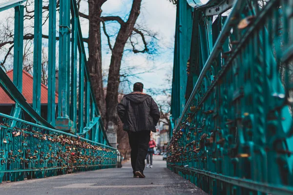 Küçük şehirde yeşil köprüden geçen bir adam.