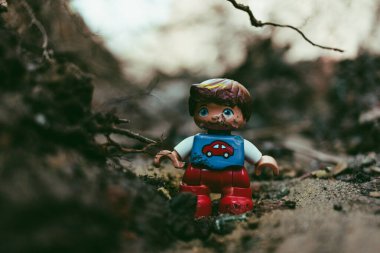 damaged toy boy figurine in red and blue with car sign on the chest