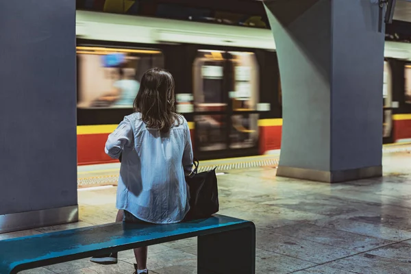 Kız metro istasyonunda bankta oturuyor.