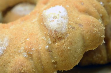 Önplanda şeker ve delikli kurabiye.