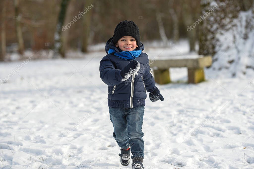 young boy playing under the snow