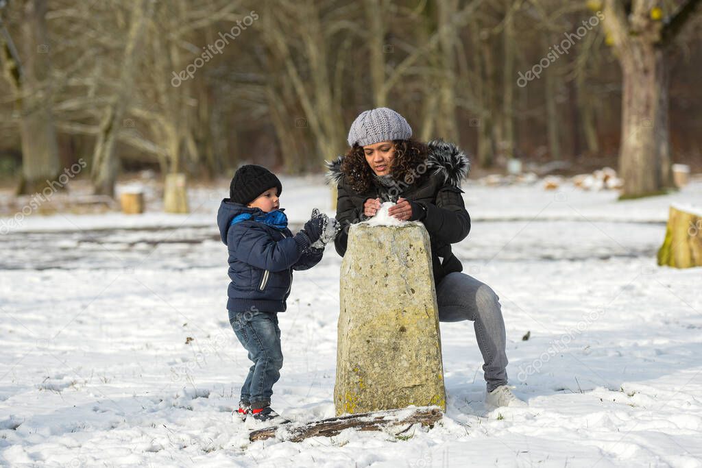 metis mother playing with her son under the snow