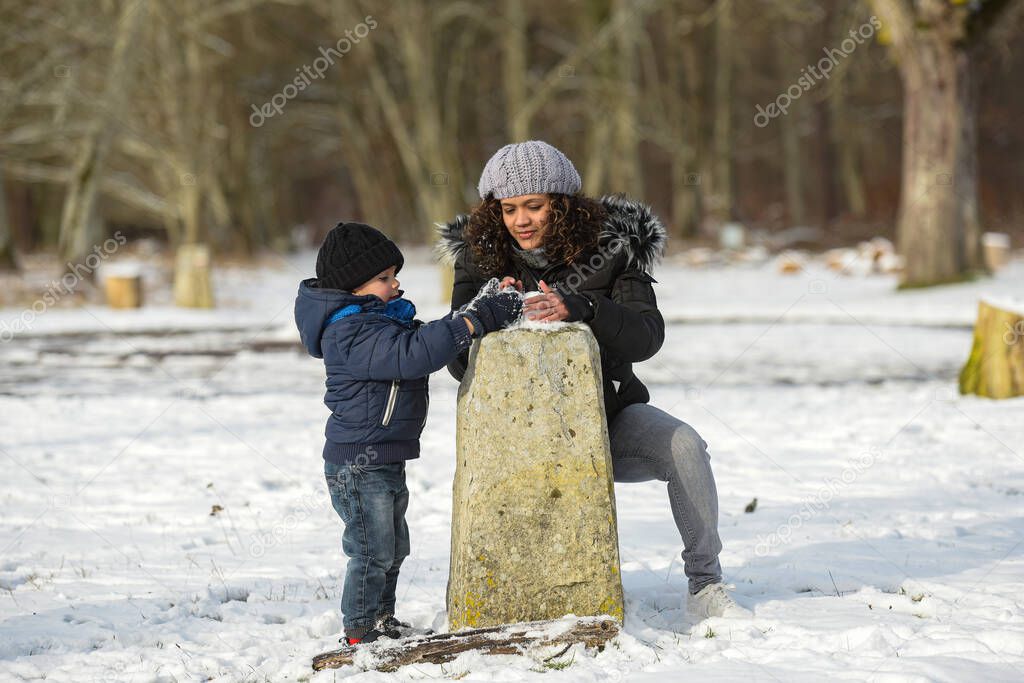 metis mother playing with her son under the snow