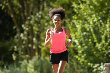 Genç bir kadın parkta koşuyor.