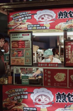 İnsanlar Gongguan Gece Pazarı 'nın yanında oturmuş modern bina ışıklarıyla aydınlanıyor ve hareketli bir gece ortamı yaratıyorlar..