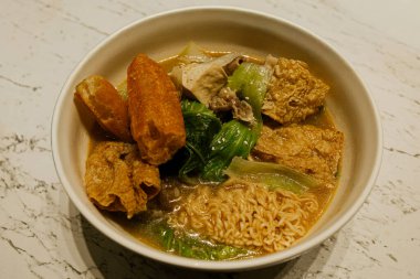 Tofu, sebze ve lezzetli et suyuyla servis edilen sıcak şehriye çorbası. Sıcak ışıklandırmalı konforlu yiyecek konsepti, Asya mutfağına uygun, ev yapımı yemekler, ve gündelik yemek temaları.