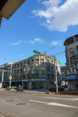 Açık mavi gökyüzü altında ikametgah ve ofis binalarının yer aldığı modern şehir manzarası. Temiz sokaklar, açık kamusal alanlar ve yeşillik çağdaş şehir yaşamını ve mimarisini yansıtıyor.