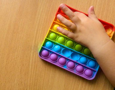 child with colorful pop it game. Close-up of a child's hand playing with a colorful pop it toy