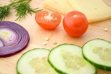 Sebze ve peynir dilimlenmiş bord. Soğan, salatalık ve domates malzemeleri..