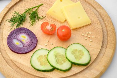 Peynir ve sebzeler doğrama tahtasında. Soğan, salatalık ve kiraz domatesleri..