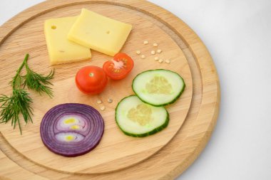 Peynir ve sebzeler doğrama tahtasında. Soğan, salatalık ve kiraz domatesleri..