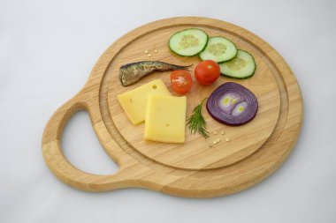 Peynir ve sebzeler doğrama tahtasında. Soğan, salatalık, vişneli domates ve baharat karışımı..